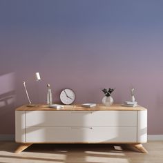 a white dresser with two clocks on it in front of a purple wall