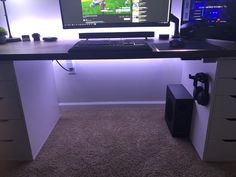 a computer desk with two monitors and a keyboard on it in front of a white wall