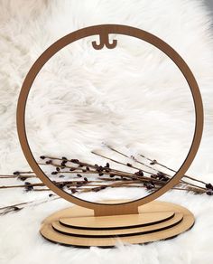 a round mirror sitting on top of a white fur covered floor next to dried flowers