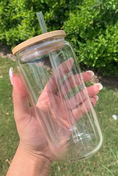 a person holding a glass jar with a straw in it