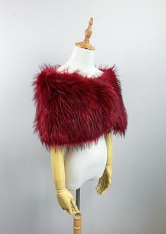 a mannequin wearing a red and white fur stole on top of a wooden stand