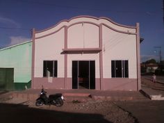 a motorcycle is parked in front of a pink and white building on the side of the road