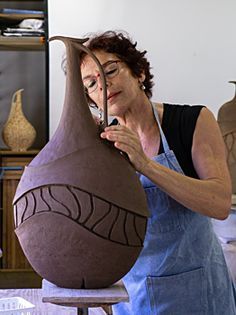 a woman is working on a vase in her studio