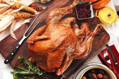 a turkey on a cutting board with other thanksgiving foods