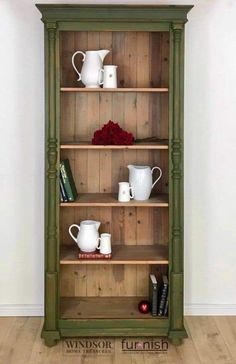 a green bookcase filled with lots of books next to a white vase and red rose