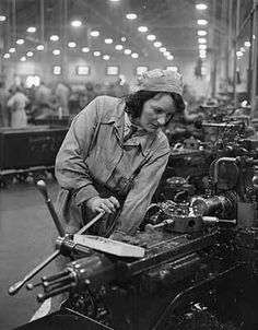 an old black and white photo of a woman working in a factory