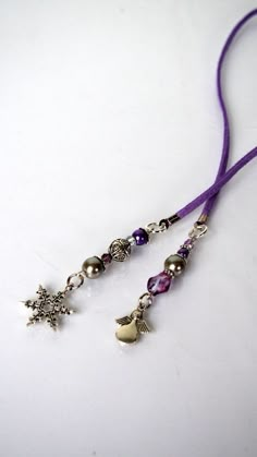 a purple lanyard with two charms and a star on the end is sitting on a white surface