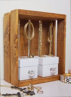 two white boxes with gold chains and rings in them sitting on a table next to other jewelry