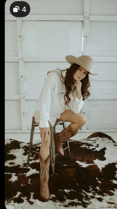 a woman sitting on top of a chair wearing a cowboy hat