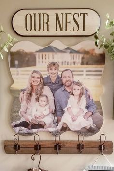 a family photo hanging on a wall with hooks and a sign that says our nest