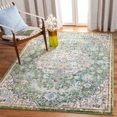 a green and blue area rug in a living room with a wooden chair, white curtains, and windows