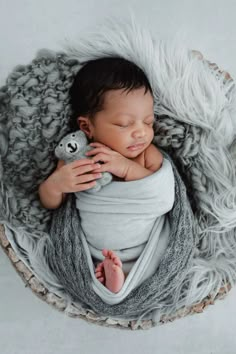 a newborn baby wrapped in a blanket with a teddy bear