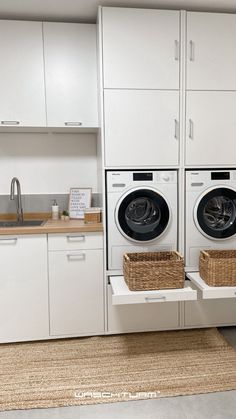 a washer and dryer in a room with white cabinets on the wall next to each other