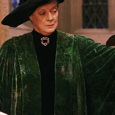 an older woman wearing a green coat and black hat