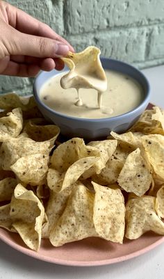 a pink plate topped with tortilla chips and a bowl of ranch dip next to it