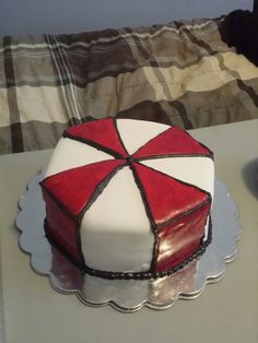 a red and white cake sitting on top of a table next to a glass plate