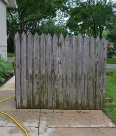 a fire hydrant connected to a wooden fence in front of a house with grass and trees