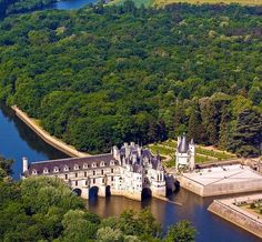 an aerial view of a castle in the middle of a river surrounded by green trees