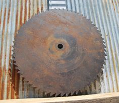 an old rusty circular saw blade on top of a metal container with rusted paint