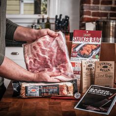 a man is holding up a large piece of meat in front of his kitchen counter