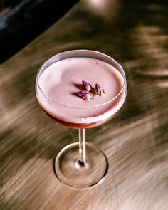 a pink cocktail sitting on top of a wooden table