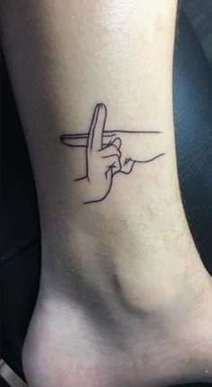 a person's foot with a tattoo on it that has a finger pointing to the sky