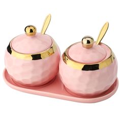 two pink pots with gold lids on a tray