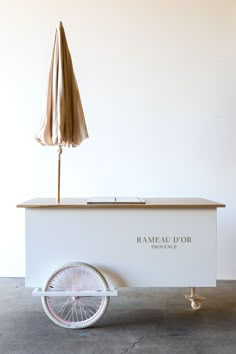 a white cart with an umbrella and some wheels on the front is sitting in a room