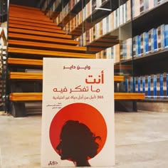 a book with arabic writing on it sitting in front of some shelves filled with books