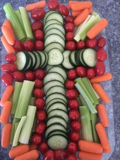 a platter filled with cucumbers, carrots, celery and tomatoes