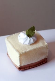 a piece of cheesecake with whipped cream and a green leaf on top is sitting on a white surface