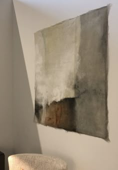 a chair sitting in front of a wall with a painting hanging on it's side