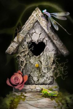 a birdhouse with a dragon on the roof and a rose in front of it