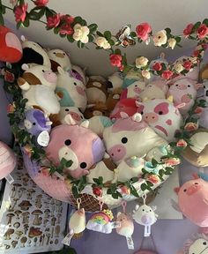 many stuffed animals are arranged in the shape of a heart and surrounded by pink flowers