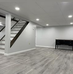 an empty room with stairs and a piano