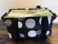 a black and white polka dot tote bag sitting on top of a wooden floor