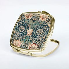 an ornately decorated compact mirror on a white surface