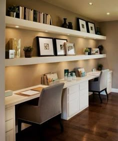 a home office with two desks and some bookshelves on the wall above them