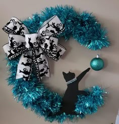 a blue and white christmas wreath with a black cat on it next to a green ornament