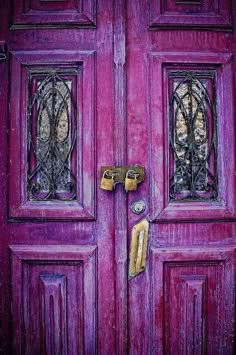 a purple door with two locks on the front and one has an ornate glass window