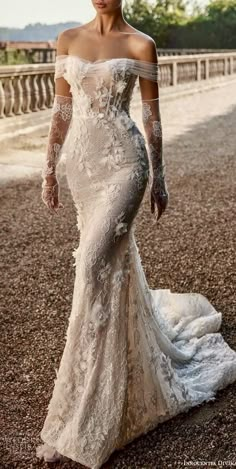 a woman in a white wedding dress standing on the ground with her arms behind her back