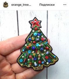 a hand holding a small christmas tree brooch