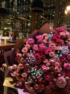 a large bouquet of pink and purple flowers sitting on top of a table in a restaurant