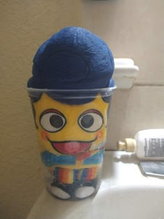 a cup that has some kind of toy on it's head in the bathroom