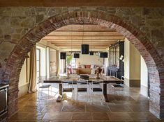 an archway leads to the living room and dining area in this modern home with stone walls