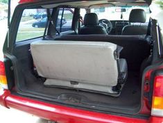 the back end of a red car with its trunk open and seats folded down in it