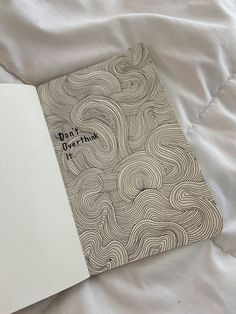 an open notebook with the words don't over think on it sitting on a bed