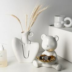 a white bear figurine sitting next to a vase filled with flowers and reeds