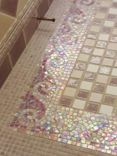 a bath tub sitting next to a toilet covered in lots of iridescent tiles