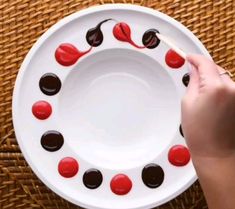 a person is holding a spoon over a plate with red and black candies on it